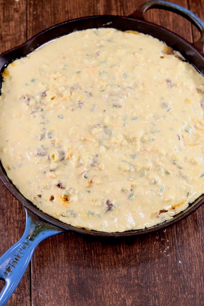Mexican Cornbread with Ground Beef in a skillet ready to bake