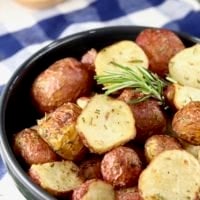 Air Fryer Roasted Potatoes with fresh rosemary in a black bowl, blue check towel