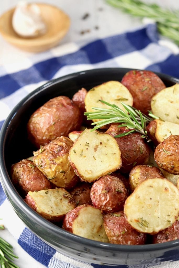Air Fryer Roasted Potatoes with fresh rosemary in a black bowl, blue check towel