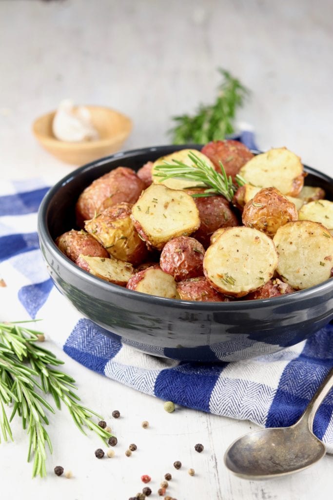 Black bowl of roasted red potatoes with rosemary