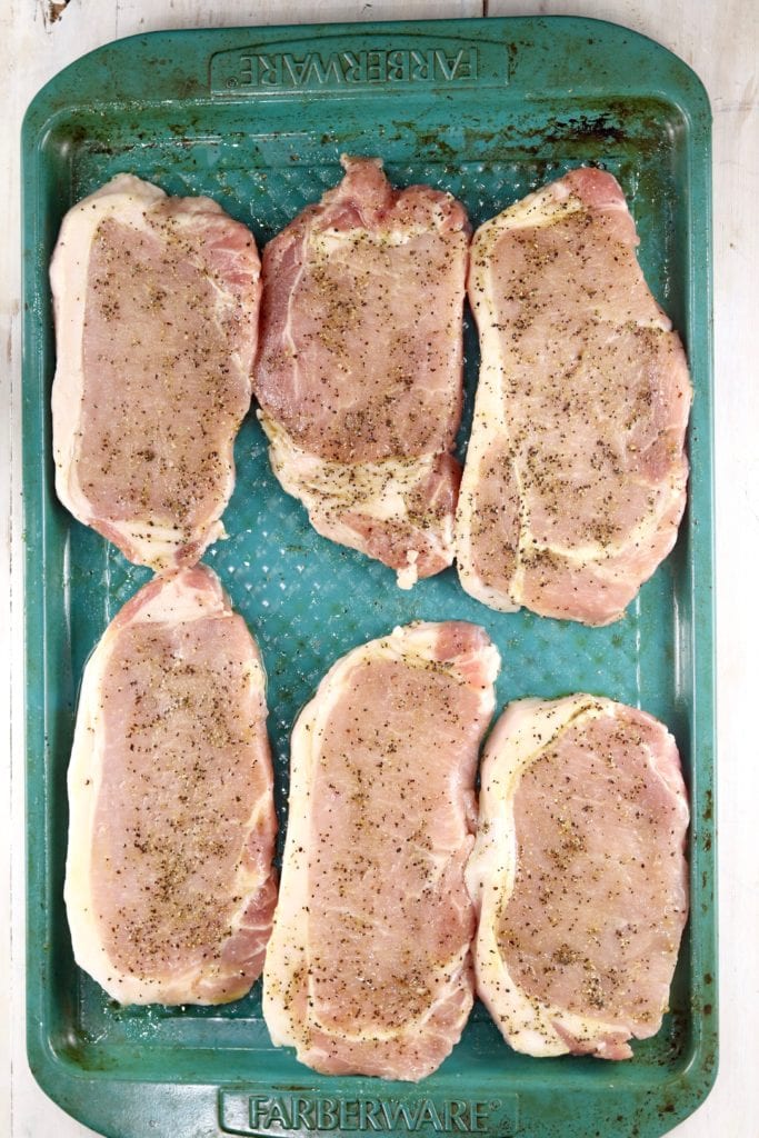 Pork Chops on a blue sheet pan seasoned for the grill