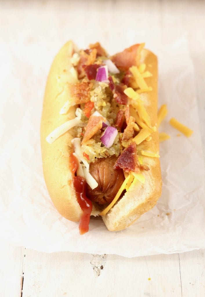 Grilled Hot Dog topped with ketchup, cheese, onion, bacon, and relish
