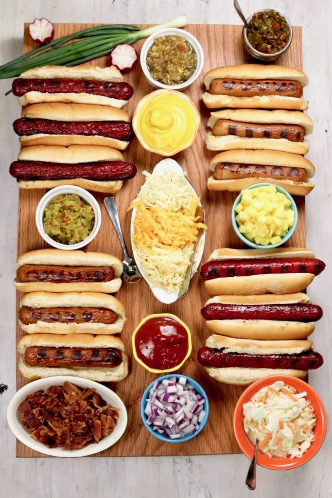 Board with grilled hot dogs and toppings