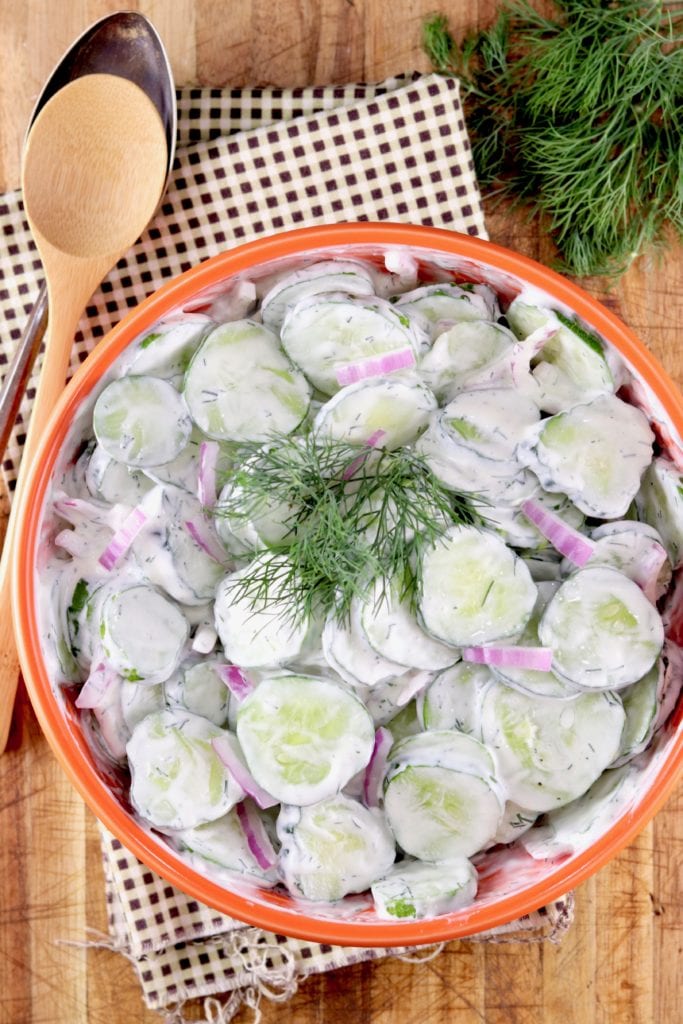 Cucumber salad with creamy dill dressing in a orange bowl