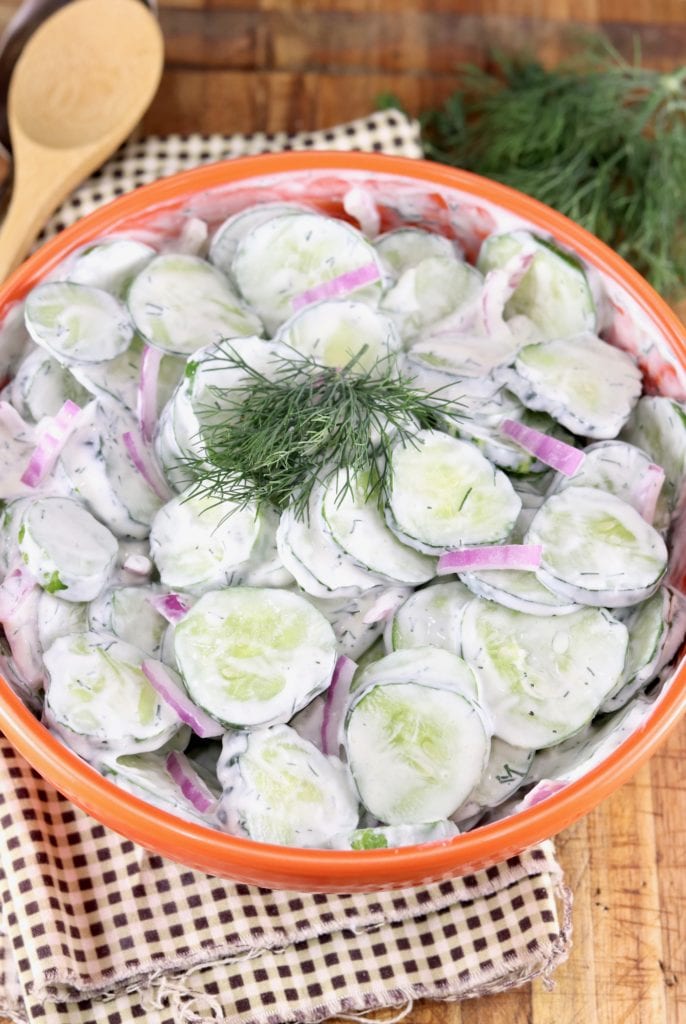 Orange bowl with cucumbers, red onion and dill dressing