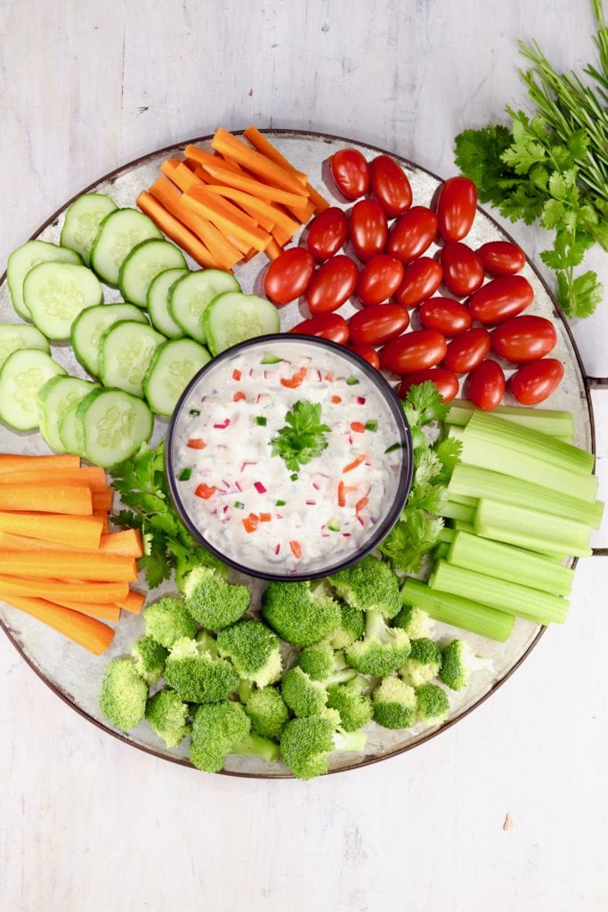 Tray of vegetables with creamy vegetable dip in the center