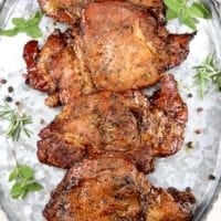 Grilled Pork Chops with fresh herbs and peppercorns on a galvanized tray