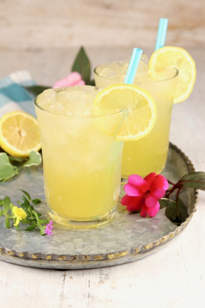 Galvanized platter with 2 glasses of lemonade, fresh flowers and lemons garnish the tray