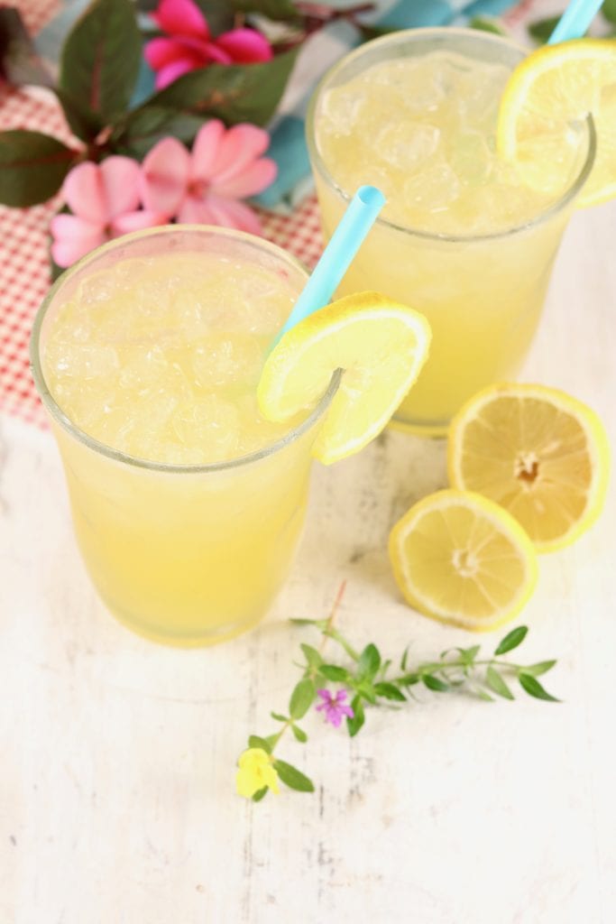Fresh lemonade in glasses with a blue straw and lemon garnish