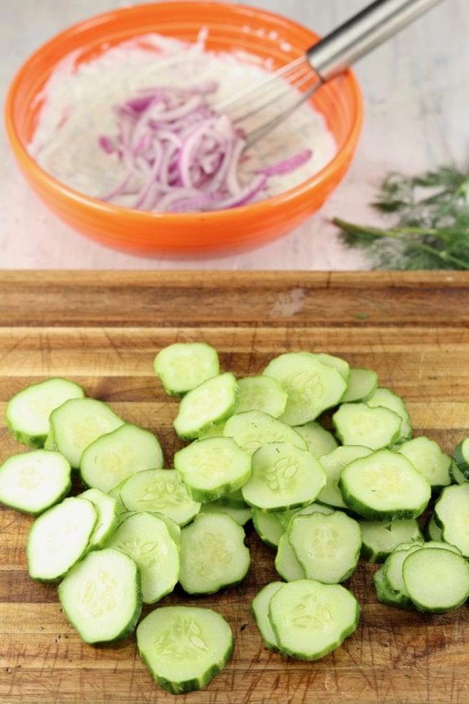 Sliced cucumbers and bowl of creamy dressing