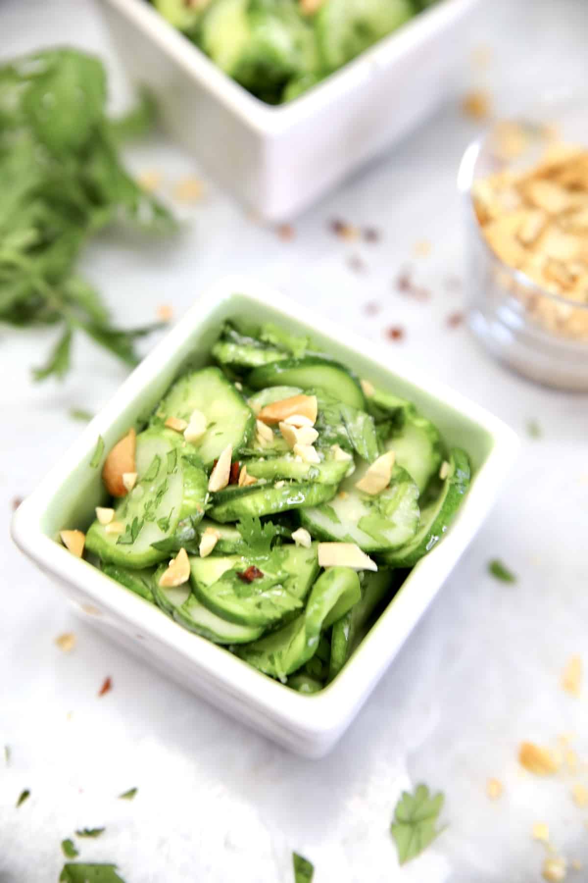 Thai cucumber salad in a square bowl with chopped peanuts.