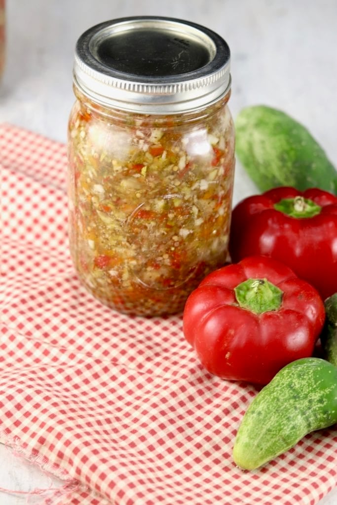 Pint jars of sweet pickle relish with red peppers and fresh cucumbers