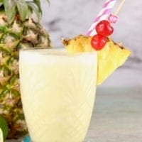 Pina Colada Mocktail garnished with fresh pineapple and cherries