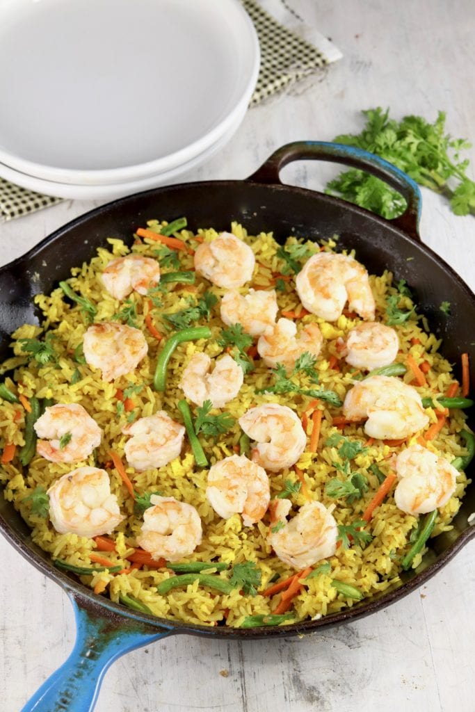 White plates and skillet of fried rice with shrimp, carrots, green beans and cilantro