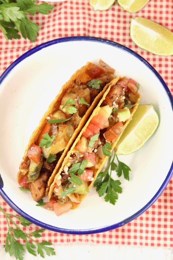 Overhead view of fish tacos with tomatoes on a white plate