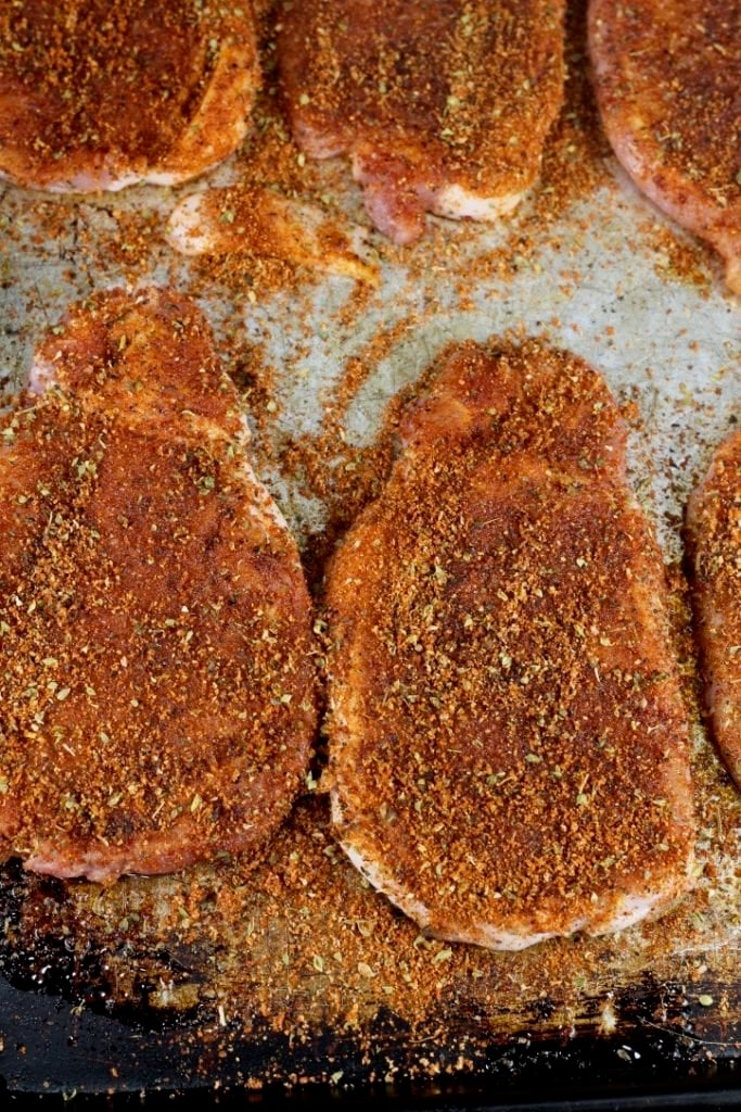 Boneless pork chops seasoned with Cajun seasoning on a sheet pan