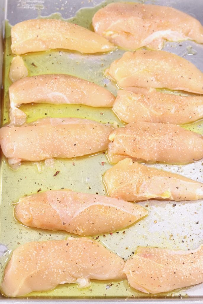 raw chicken tenders with olive oil, salt and pepper on a sheet pan