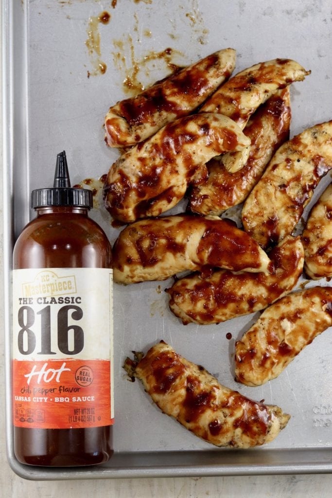 KC Masterpiece 816 BBQ Sauce and grilled bbq chicken tenders on a sheet pan