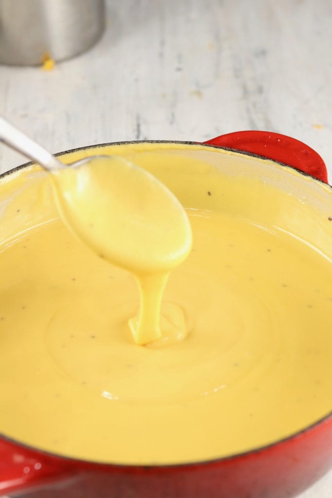 Cheddar Cheese Sauce in a sauce pan, spoon drizzling cheese