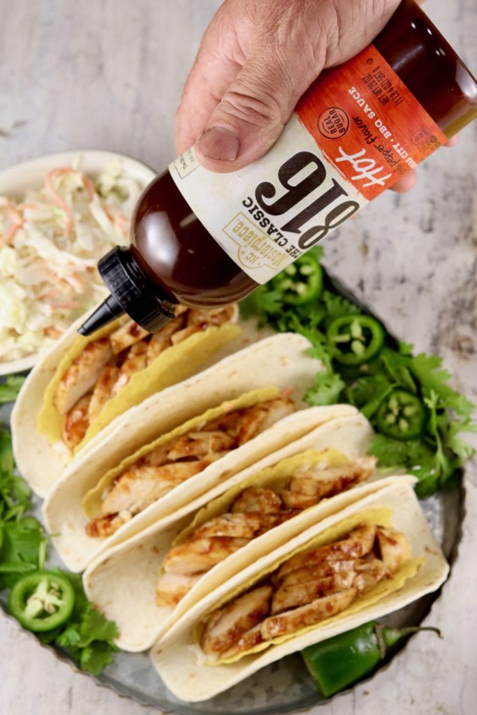Drizzling BBQ Sauce over grilled chicken tacos