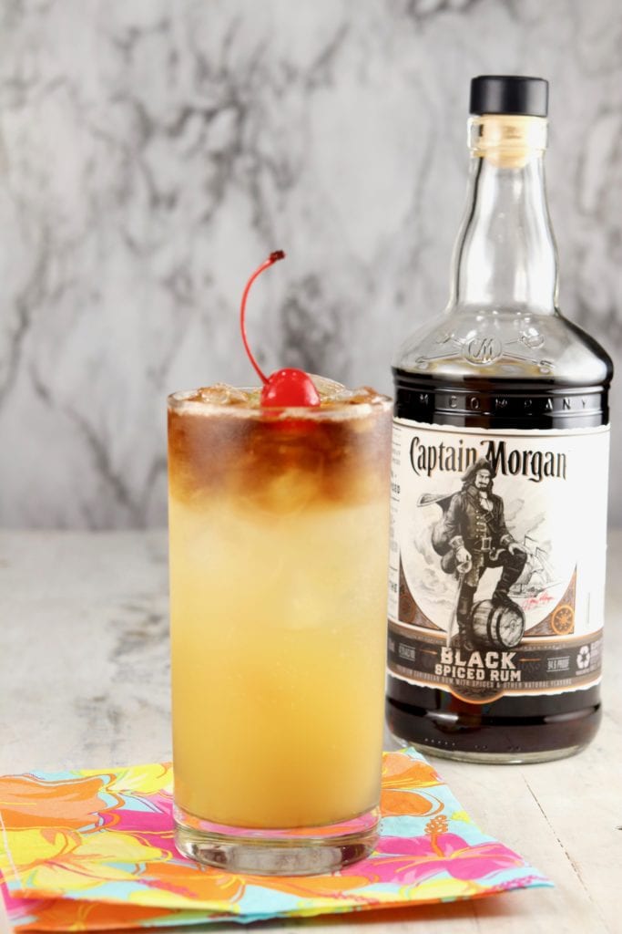 Glass of pineapple rum punch with bottle of Captain Morgan Black Rum