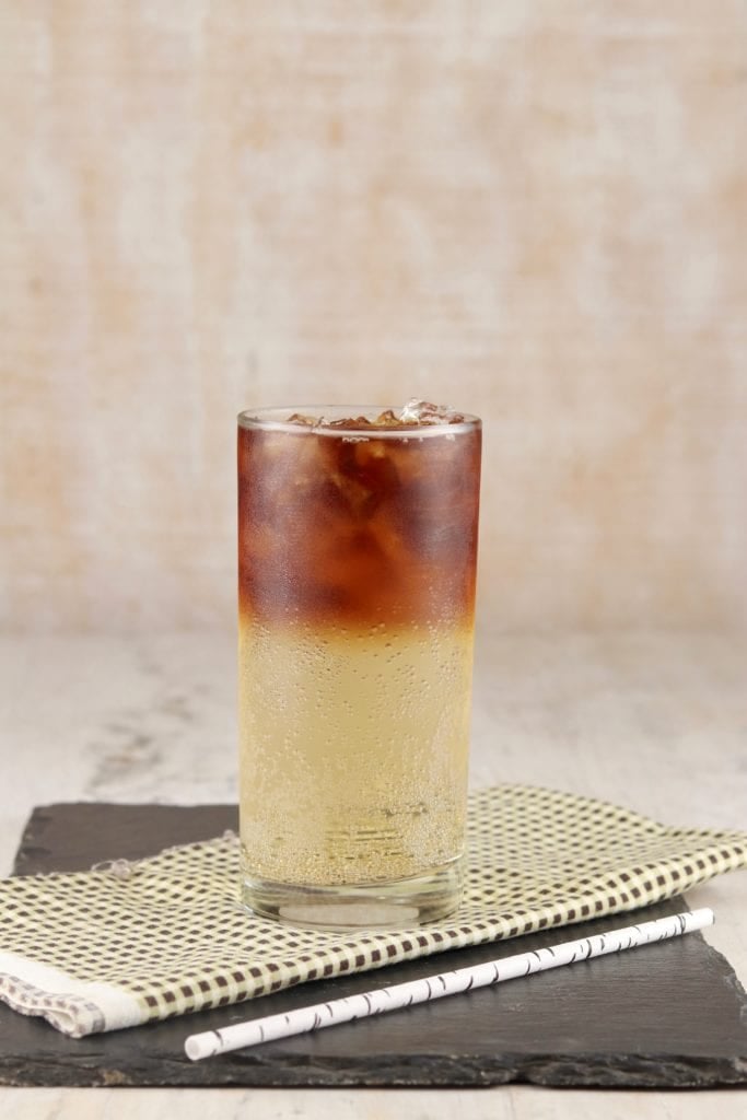 Glass of ginger ale with black rum floating on top