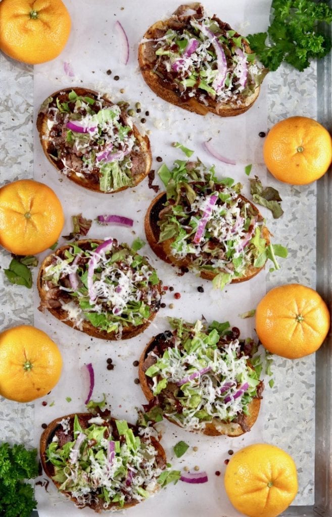 Steak Crostini on a serving tray with whole cutie oranges