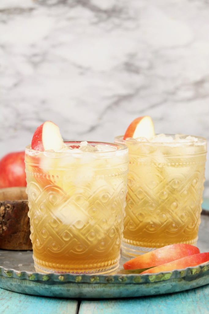 2 glasses of apple cider cocktail with apple slice garnish