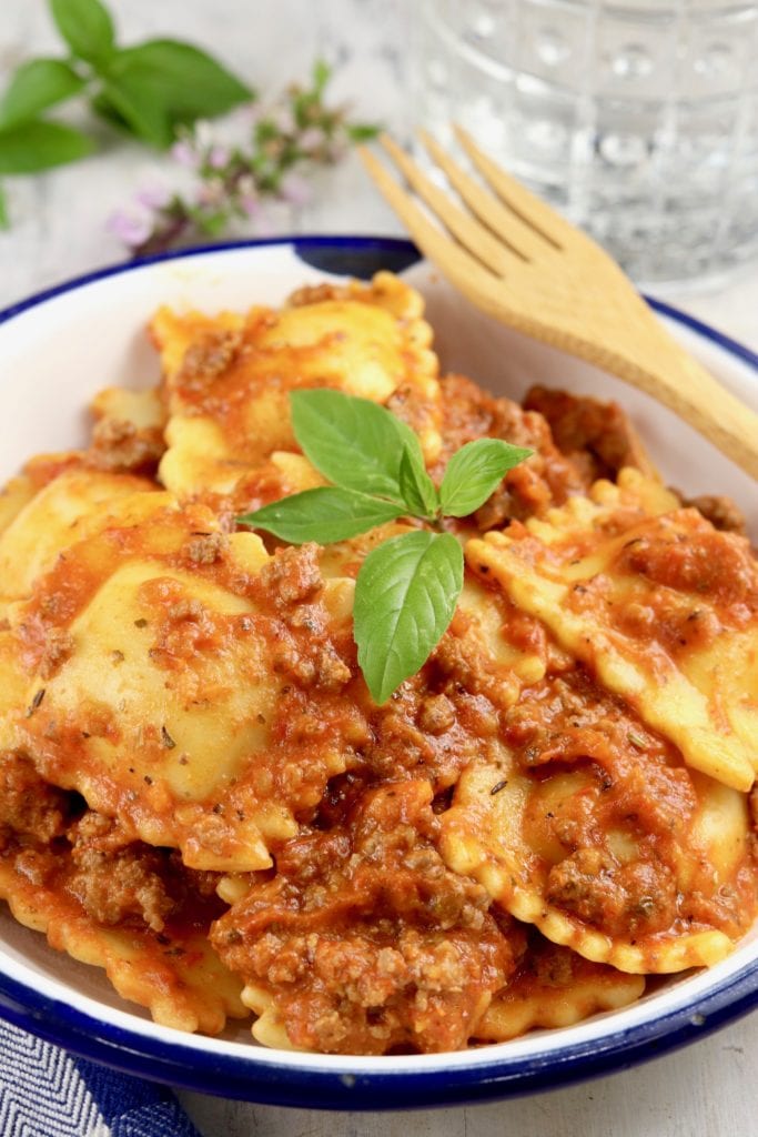White bowl of cheese ravioli in tomato and ground beef sauce