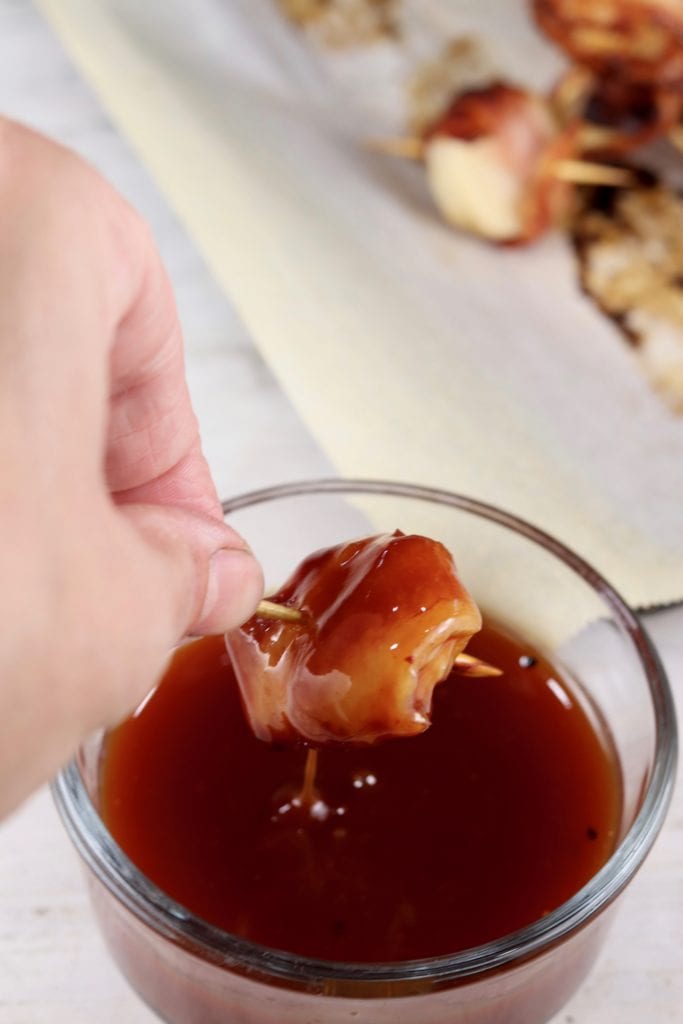 Dipping bacon wrapped water chestnuts into Barbecue Sauce Bowl