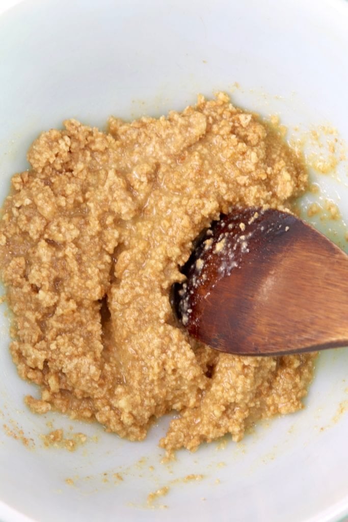 Butter and graham cracker crumbs in a bowl with wooden spoon