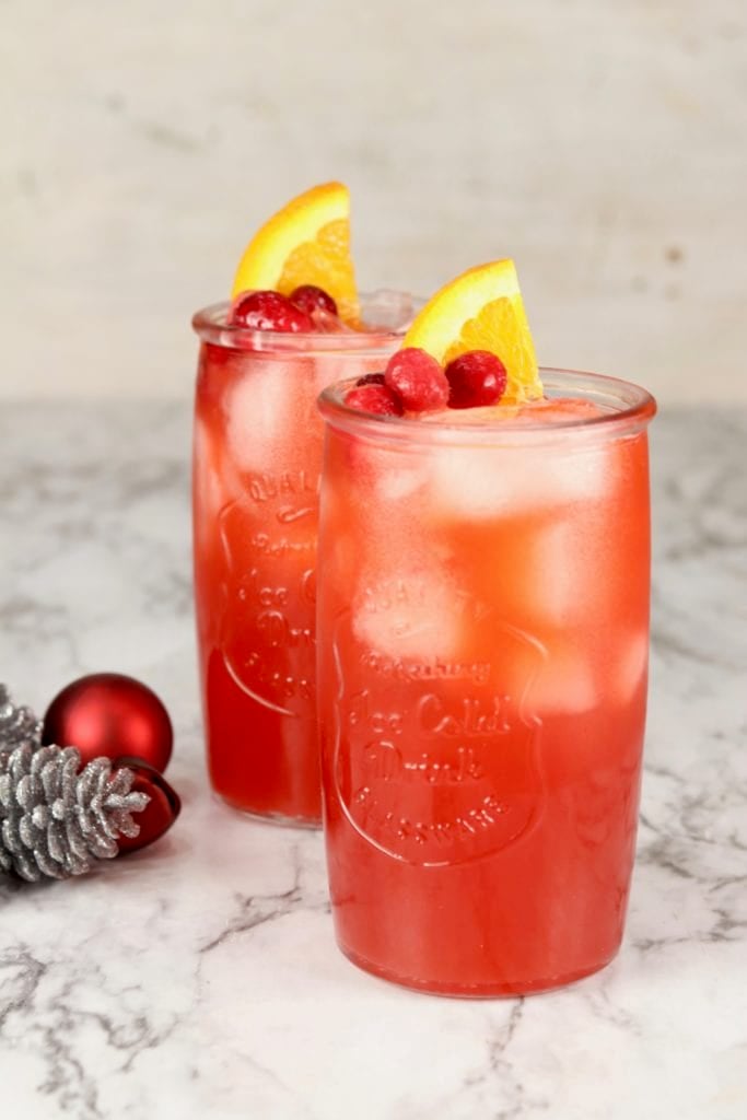 2 glasses of red holiday punch garnished with cranberries