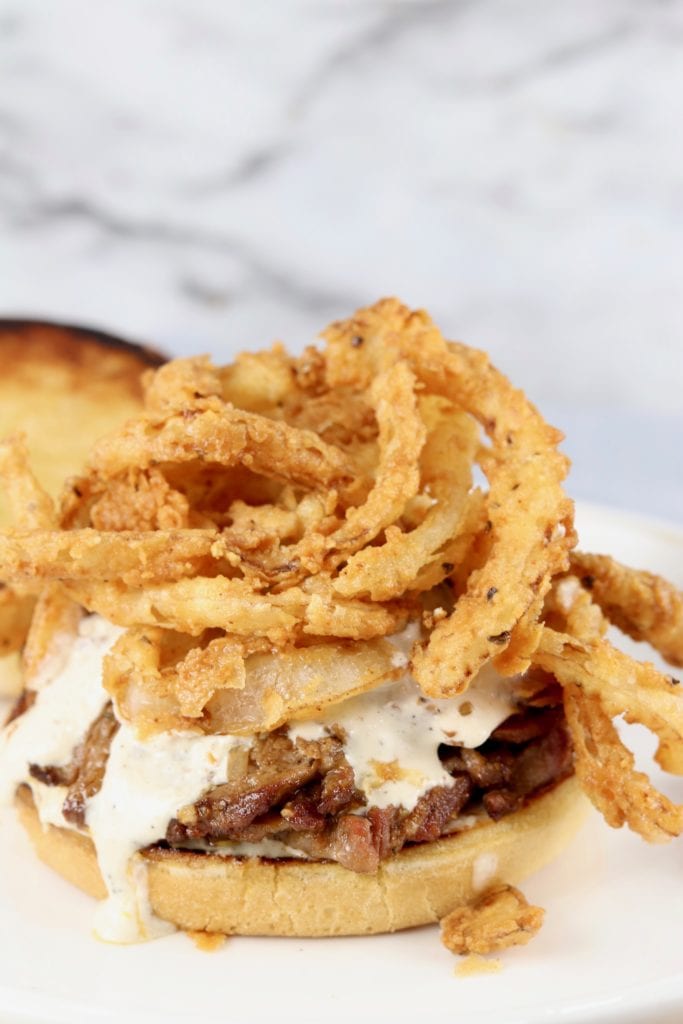 French fried onion strings on a roast sandwich with horseradish