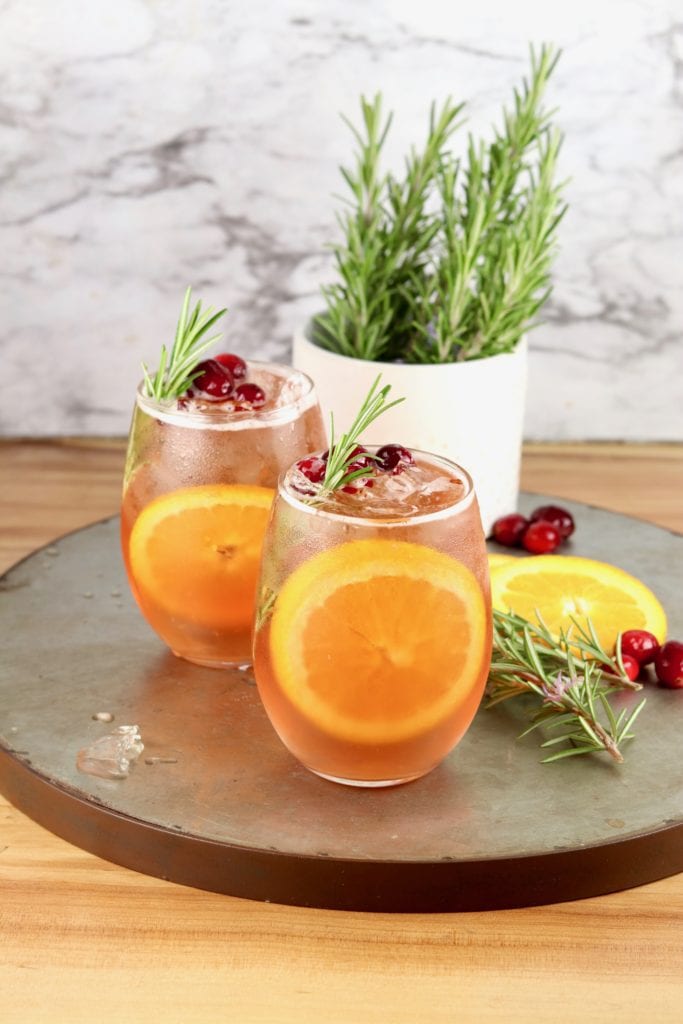 2 wine glasses with punch on a tray with fresh rosemary