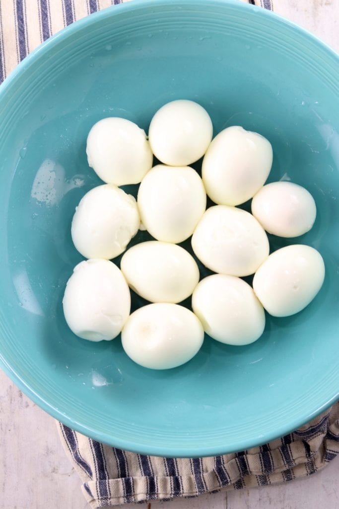 Peeled hard boiled eggs in a blue bowl
