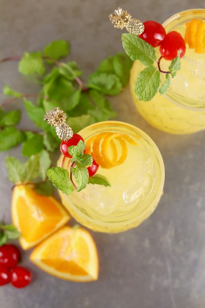 Overhead view of pineapple vodka cocktails garnished with mint and cherries