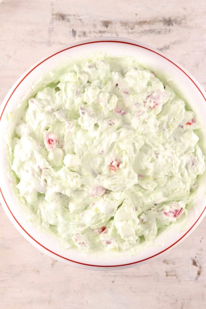 Watergate Salad is a classic potluck and holiday dish that is mixed up in about 5 minutes! Easy pistachio fluff made with crushed pineapple, pecans, cherries and pistachio pudding for a festive dish that anyone can make! Pistachio fluff holiday dessert