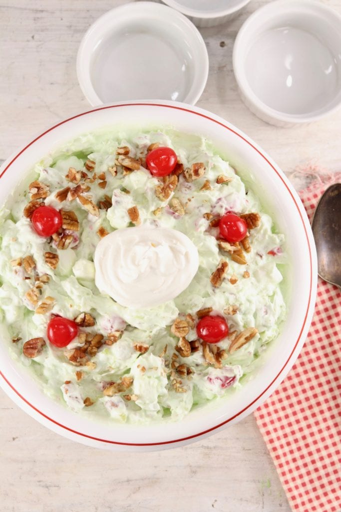Watergate Salad is a classic potluck and holiday dish that is mixed up in about 5 minutes! Easy pistachio fluff made with crushed pineapple, pecans, cherries and pistachio pudding for a festive dish that anyone can make! Overhead of Watergate Salad dessert