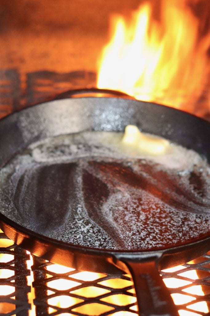 Cast iron skillet on grill with melted butter