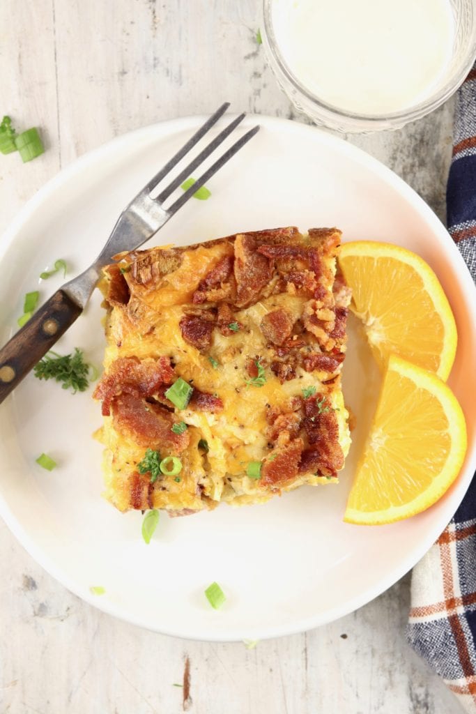 Breakfast strata slice on a white plate with orange slices