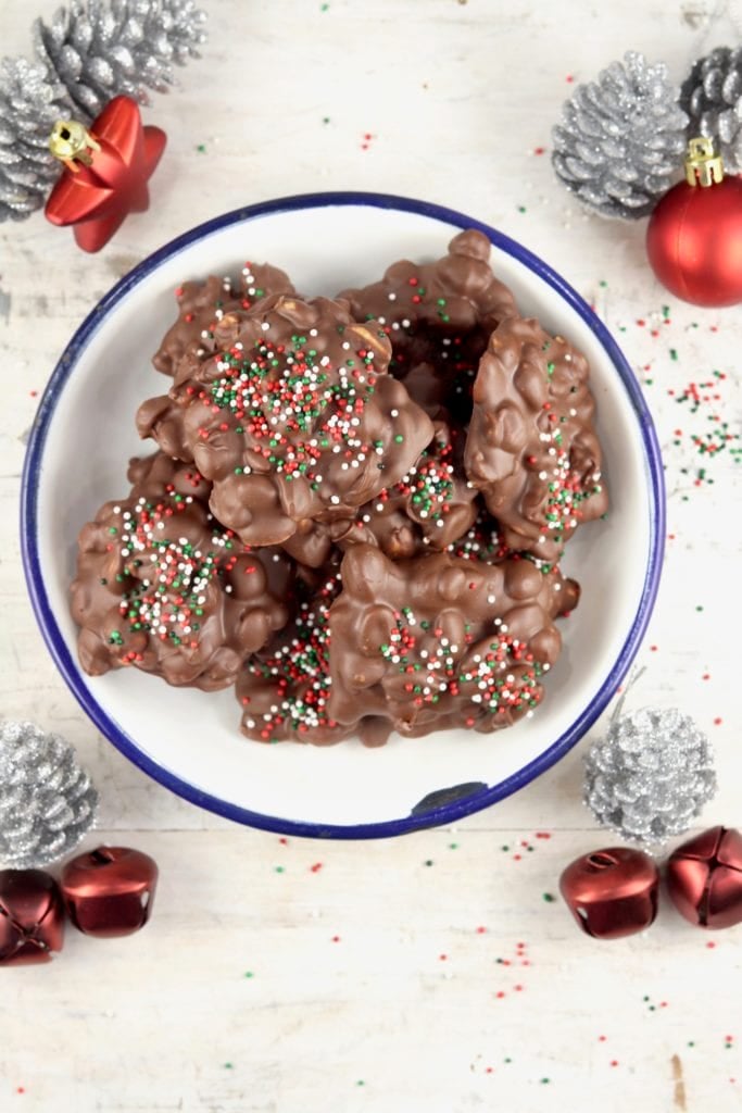 Chocolate Peanut Butter Clusters in a bowl surrounded by Christmas ornaments
