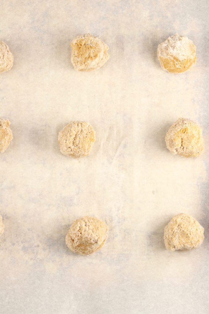 Molasses cookie dough balls on a parchment lined baking sheet