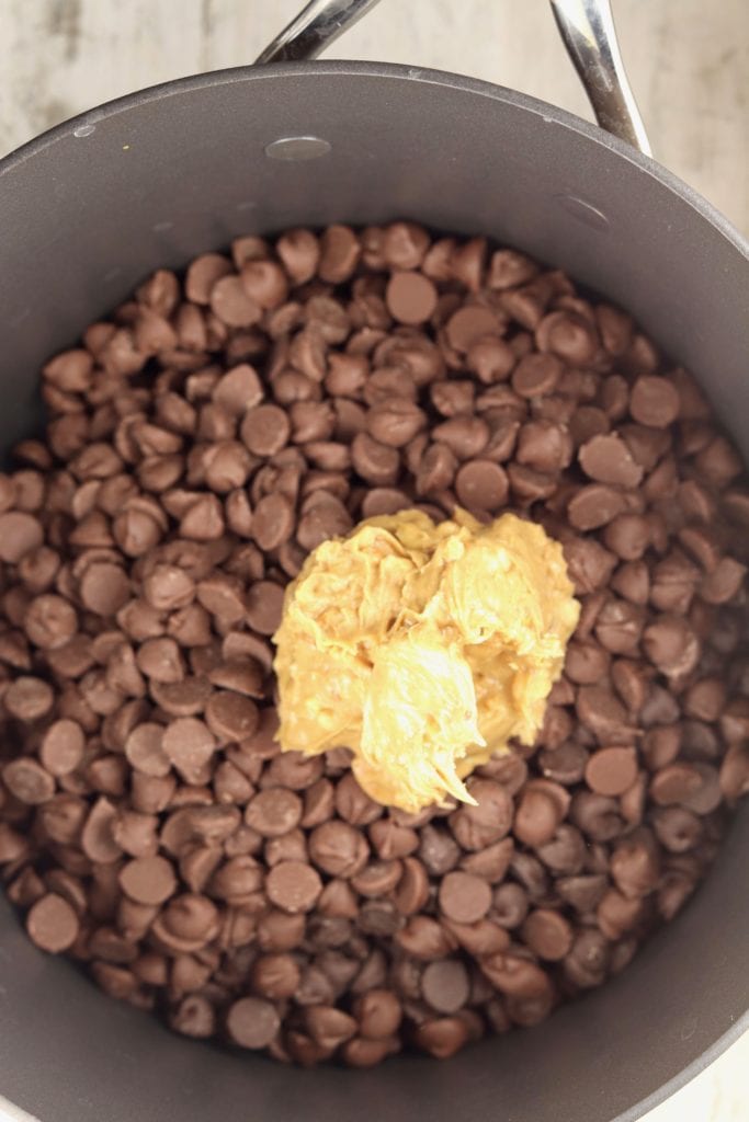 Chocolate chips and peanut butter in a pan for peanut clusters