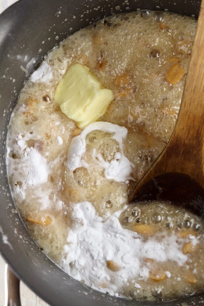 Adding butter and baking soda to peanut brittle mixture