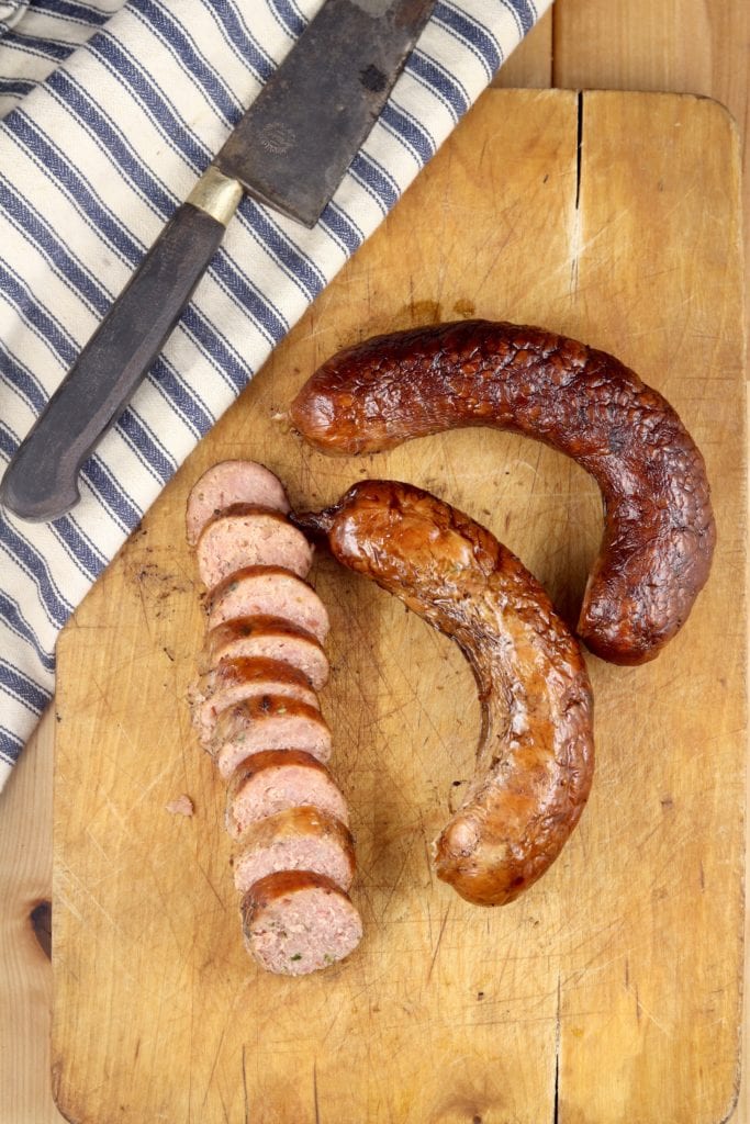 Wood cutting board with sliced smoked sausage and 2 links