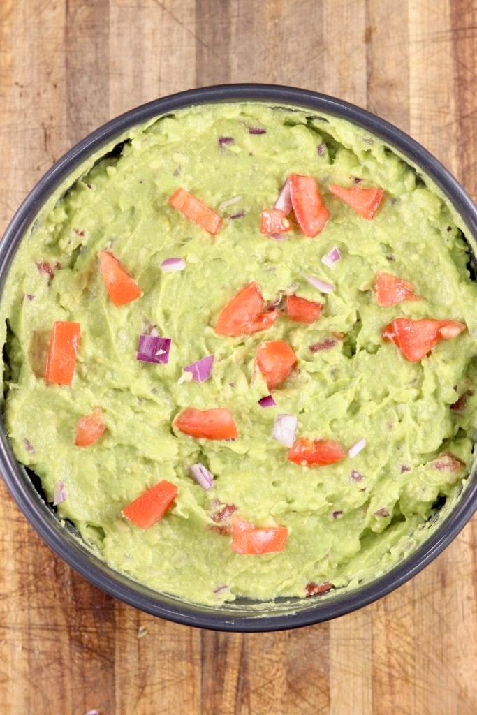 Bowl of guacamole with tomato and onion