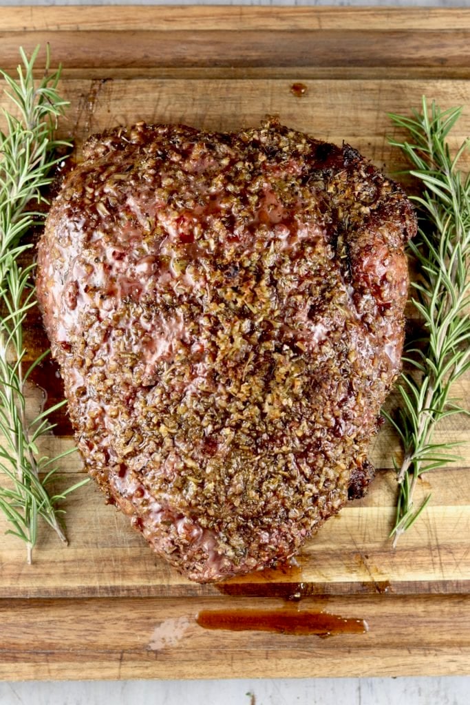 Herb Crusted roast on a cutting board with fresh rosemary 