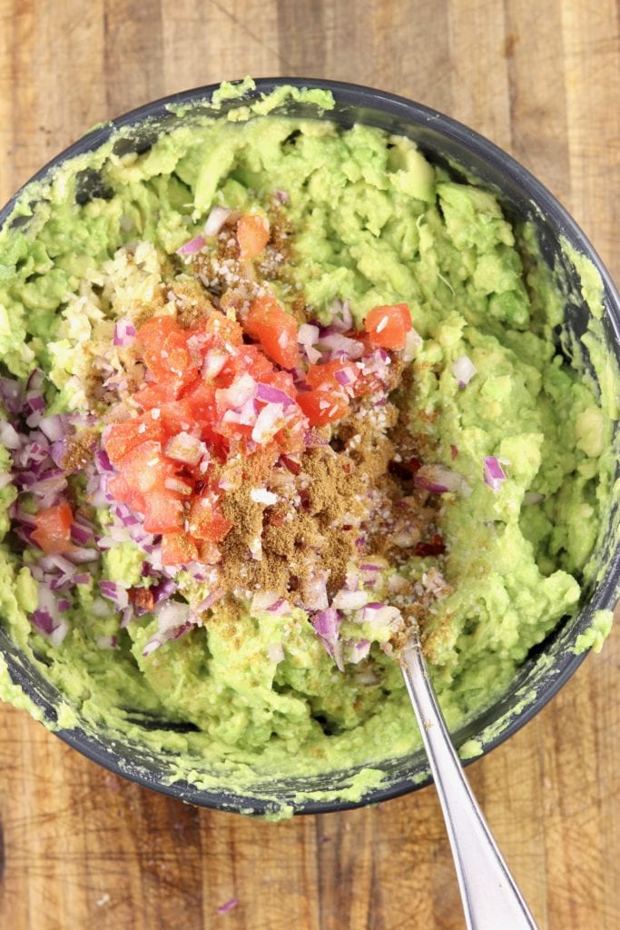 making guacamole with diced tomatoes and red onions
