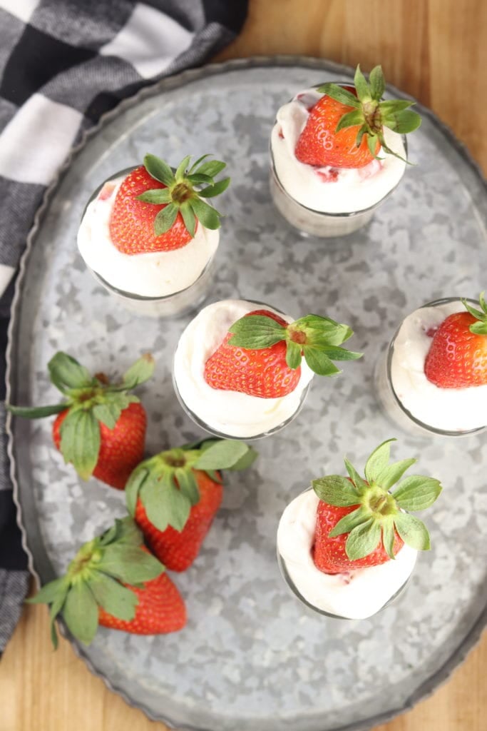 Strawberry topped cheesecake shooter desserts on a galvanized tray
