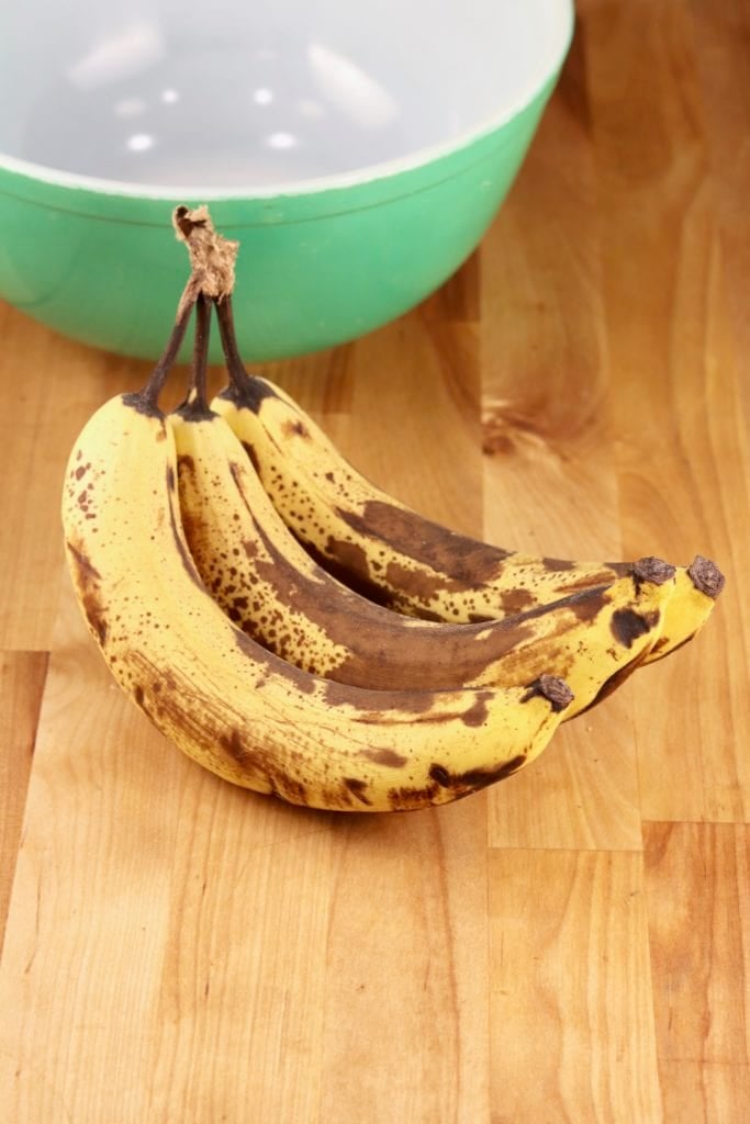 Ripe bananas on counter with a green bowl